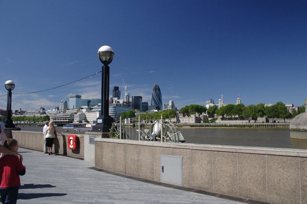 South bank of Thames next to the London Assembly buildings, looking towards the City of London - both the Swiss Re Tower and the Nat West Tower can be seen.