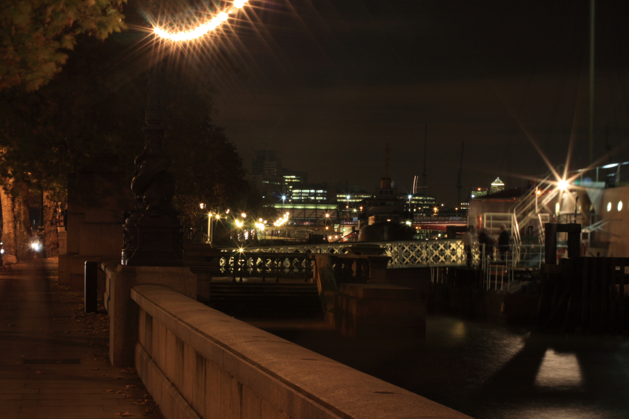 Boats on the Thames at night infront of the London sky line.
