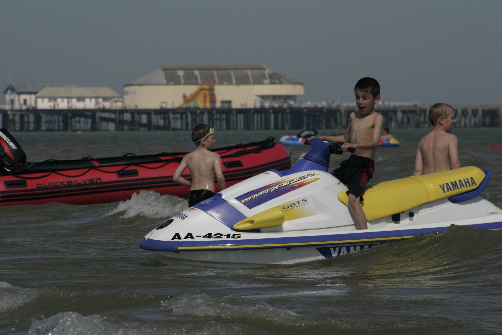 Kids enjoying the sun on jet skis at Clacton-on-Sea with the pier in the background.